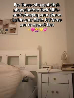 A bedroom scene, focused on a bed with white bedding. A white nightstand is on the right, displaying a lamp, books, and what appears to be a charging phone. Text overlay indicates motivational message placed above the room setting.