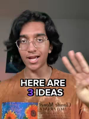 A young man with dark hair and glasses is centered in the frame, with text reading 'HERE ARE 3 IDEAS' overlaid. He's smiling and gesturing with his right hand. In the foreground, a small painting of sunflowers is visible. The background appears to be a domestic setting, the colors are warm tones of orange and brown.