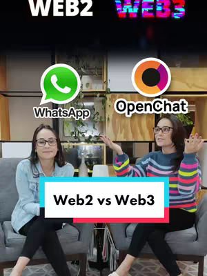 The image shows two women seated on gray chairs. On the left, a woman wearing glasses, a light blue denim jacket, and black pants. On the right, another woman with glasses, a blue and white striped long-sleeve shirt, and black pants, is gesturing with her hands. Behind them are graphic logos of WhatsApp and OpenChat respectively. Above the logos are texts in the shape of "WEB2" and "WEB3". Below the women is a white rectangle with the text "Web2 vs Web3".