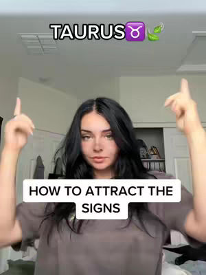 The cover image shows a woman with long black hair in a bedroom setting. She is looking at the camera with both hands pointing upwards. Text overlays include "TAURUS" at the top and "HOW TO ATTRACT THE SIGNS" in a white rectangular box, positioned at the bottom portion of the frame. The background shows a white wall, a vent, and a closed door in the background.