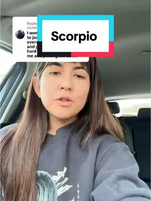 A woman with long brown hair is seated inside a vehicle, likely a car, with a comment overlay in the upper left corner. A colored rectangle overlay is positioned above the woman's head, with the word "Scorpio" written in white text. The woman appears to be filming herself, and the scene suggests a vlog or casual video.