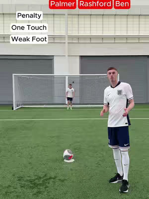 The image shows a soccer field with a player in a white jersey, black shorts, and white socks standing in the center. A soccer ball is in front of him. In the background, there's a net, and another person is further away. The text overlay has the words Penalty, One Touch, and Weak Foot.