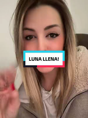 A close-up shot features a woman with long blonde hair looking towards the camera. She has dark eyeliner and blush, and a colorful text overlay of "LUNA LLENA!" covers her mouth. She wears a light-colored, textured sweater, and the background is softly blurred.