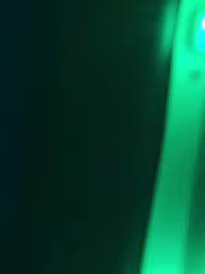 Abstract image with a mostly dark green background. A streak of bright green light runs diagonally from the bottom right towards the top left, creating a contrast in tones. The composition is simple and modern, emphasizing color and form.