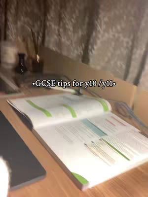 An open book on a wooden desk is the focal point, with text overlayed at the top. The book's pages are open, with visible text and highlighted sections. A notebook and other stationary are near the book, indicating a study environment. The lighting is soft and natural.