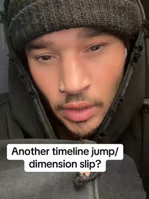 A man with a beard and a beanie hat looking directly at the camera. Overlaid text in a white box reads: 'Another timeline jump/dimension slip?'. The background is dark.