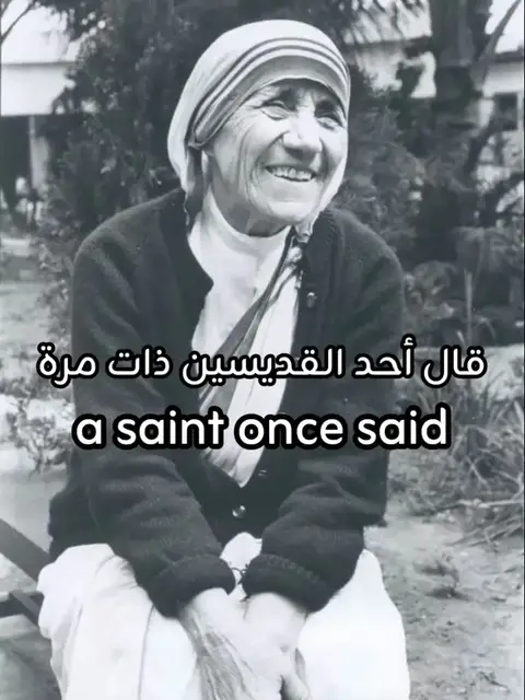 A grayscale photograph features Mother Teresa, the central figure, smiling warmly. She is wearing a simple white head covering with stripes, a dark sweater, and a white top. The background is blurred, suggesting a garden or outdoor setting. Text overlays are present at the bottom, adding context to the image.