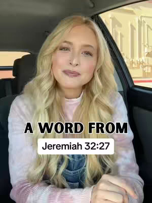 A woman with long blonde hair smiles gently while sitting in the driver's seat of a car. The image is lit softly, with the woman as the central focus. Text overlayed on the bottom of the image reads, "A WORD FROM Jeremiah 32:27". The background is slightly blurred, showing the interior of the car and the suggestion of an outdoor setting.