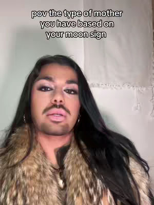 A person with dark hair, makeup, and a fur collar is centered in the frame, with text overlayed.