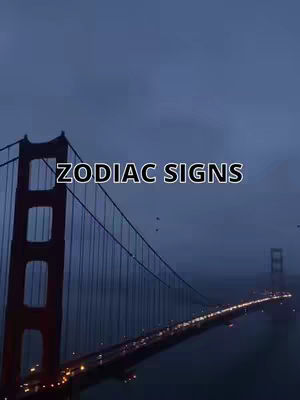 The image shows a photograph of the Golden Gate Bridge in San Francisco. The bridge is the main subject, spanning across the frame against a sky that is dusky, a deep blue, and somewhat obscured by clouds. The bridge's red hue creates a striking contrast against the dark background. Lights from cars are visible on the bridge, indicating traffic at night. Overlaying the image is the text "ZODIAC SIGNS", in a white font outlined in black, positioned prominently in the center of the frame.