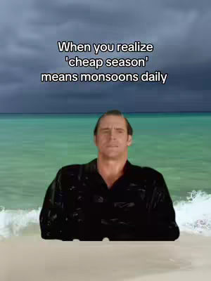 The cover image shows a man standing in water on a beach. Above him is an ocean scene with dark, cloudy skies. Overlaying the scene is white text that reads: "When you realize 'cheap season' means monsoons daily".