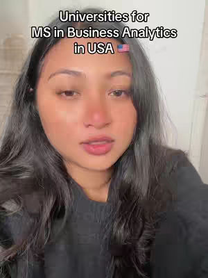 A woman with long dark hair is centered in the frame, looking directly at the camera with a neutral expression. Above her is a text overlay that reads 'Universities for MS in Business Analytics in USA' with a small American flag. The overall tone is informational, with the focus on the person and the text.
