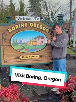 A man stands in front of a sign for "Boring, Oregon," pointing towards the sign with one hand and holding his other hand up near his face. The sign is brown with a colorful illustration of a scene in the center and the words "Boring Oregon" in large, yellow letters across the top. Overlaid on top of the image is a white and turquoise rectangle with text.