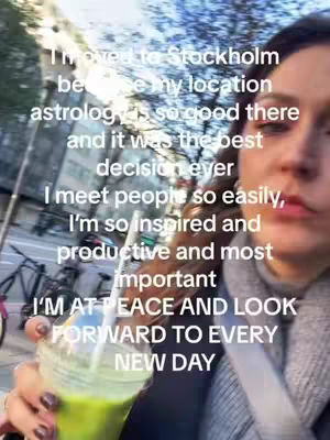 A selfie-style video shot of a woman holding a green smoothie. Text overlaid on the image highlights the benefits of her living in Stockholm due to astrology.