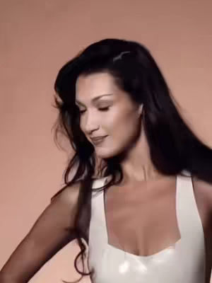 The cover image features a woman with long, dark hair, facing slightly downward with a subtle smile. She's wearing a white top with a square neckline against a plain, light-brown background. The lighting appears soft, highlighting her features.