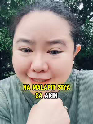 The cover image is a selfie-style shot of a woman, framed from the chest up. She is smiling slightly and looking towards the camera. Across the image, a yellow-background text overlay reads, "NA MALAPIT SIYA SA AKIN." The background shows a mix of green foliage, suggesting an outdoor setting. The woman is wearing a light green shirt with a ribbed texture and a pearl earring is visible.