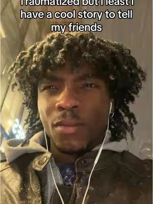 A selfie-style shot of a young man with dark hair and a neutral expression. He is wearing a jacket and an earphone, and there is text overlaying the image. The background appears to be outdoors in a cold environment, possibly snowing or frosted..