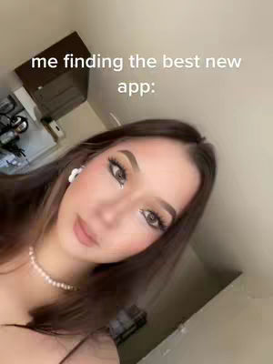 A young woman is shown in a selfie-style video, angled upward, highlighting her face and upper body. She has long brown hair, and her makeup is styled with prominent eye shadow, blush, and lip color. She wears a pearl necklace and earrings. The background is blurred but suggests a room's interior. Hook text overlays the top of the image.
