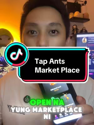 A close-up shot featuring a man in a white shirt holding a smartphone. The phone screen displays an app interface. The man looks directly at the camera, with the app's name, "Tap Ants Market Place" in overlayed textbox, indicating a product launch or announcement. The tiktok logo is in the image.  The background is blurred with warm lighting.