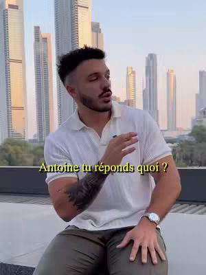 A man in a white polo shirt and olive-green pants sits with a city skyline in the background. A yellow text overlay appears on the image.