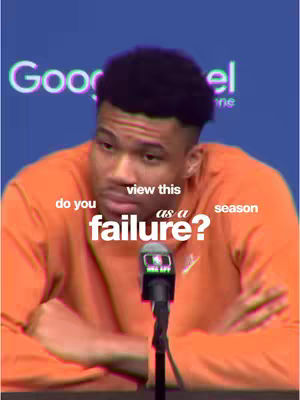 A man in an orange shirt sits in front of a microphone with text overlaid reading 'Do you view this season as a failure?'