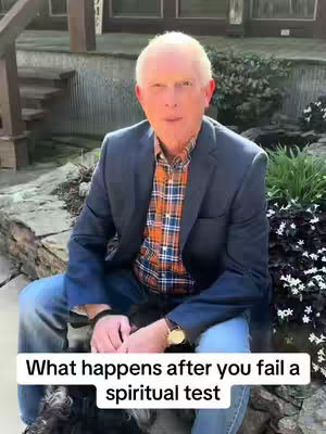 A man is sitting outdoors in front of a stone ledge, some plants, and a building. He is wearing a blue blazer over a plaid shirt and jeans. Text on the image reads, "What happens after you fail a spiritual test."