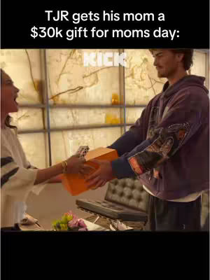 A man is handing an orange gift box to a woman, framed with blurred background of a window.