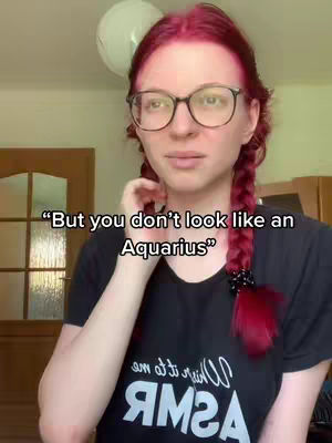 A young woman with red hair in braids wearing glasses and a black shirt, looking slightly to the side with a questioning expression. Text overlayed on the image.