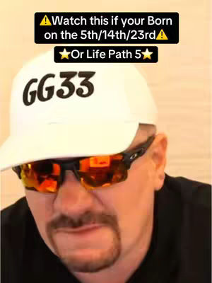 A man wearing a white cap with 'GG33' printed on it, black sunglasses with reflective orange lenses and a black shirt. The background is a plain wall. Above the man's head is a black rectangular box with white text.