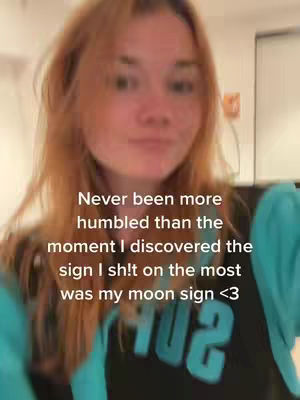 A slightly blurred selfie-style shot featuring the creator facing the camera. The background is out of focus, suggesting an indoor setting. The creator has reddish-brown hair and is wearing a turquoise top and a black shirt underneath. Overlayed text in white font is visible, detailing a personal reflection.