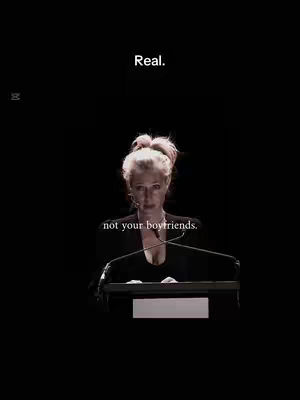 The cover image has a woman centered with a dark background and the phrase "Real." at the top. The woman is fair skinned with her hair up in a bun, wearing a black top with a lectern at the bottom providing a background.