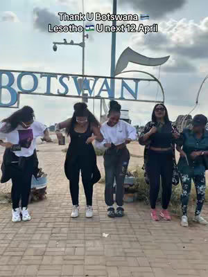 Five women are shown dancing on a paved surface, likely outdoors. The background includes the Botswana sign and a partly cloudy sky. Text overlaying the image reads, 'Thank U Botswana Lesotho U next 12 April'.