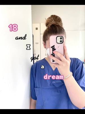 A young woman in medical scrubs takes a mirror selfie, holding a pink phone that obscures her face. Text overlays read '18 and I got a dream' in playful fonts.
