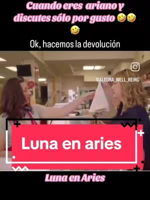 An image from a video features a scene set in what appears to be a store or service counter environment. Two women are the focus: one, with long dark hair, extends her hand toward another, with the light hair, who is positioned near the counter. A highlighted text box in vibrant red across the bottom reads "Luna en aries".
