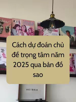 The image shows a wall with several vintage record albums, some with visible cover art. In the foreground, a light beige rectangular sign overlay displays Vietnamese text. Below this, a vintage Victrola record player is partly visible.