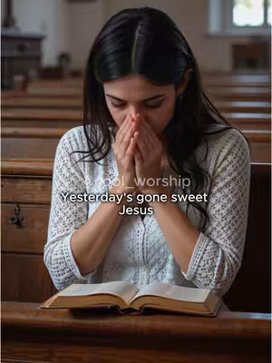 A medium shot shows a woman in a church setting. She is seated at a wooden pew, with an open book in front of her. Her hands are clasped together in prayer, and she is looking down. The background shows more pews and a window. The overall tone is one of reflection and solemnity.