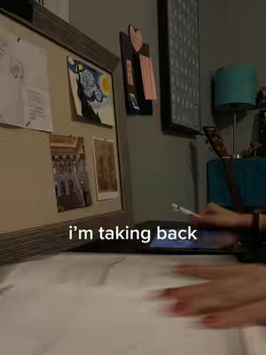 The cover image shows a desk with a whiteboard, artwork, and an iPad. A hand with red nail polish is holding a pen over the iPad, suggesting someone is taking notes or working. The environment is softly lit, with various decorative items on a shelf and wall.