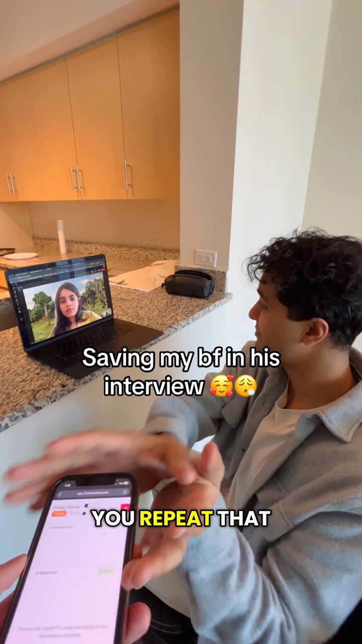 The cover image shows a person holding a phone in the foreground with text "YOU REPEAT THAT" overlaid. In the background, there's a person sitting in front of a kitchen area with modern cabinetry, a laptop displaying a video call with a woman on the screen. The overall shot suggests a tech setup, likely recording or assisting in the call. The lighting is natural, and the color palette is fairly neutral.