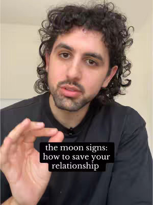 A man with curly dark hair and a short beard is centered in the frame. He wears a black t-shirt. The background is a solid, neutral color. At the bottom of the frame, a black rectangle contains the overlay text.