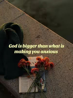 The image presents a composition of muted tones centered around a stone surface that occupies the majority of the frame. In the foreground, a bouquet of reddish-orange flowers is placed over a stack of vintage newspapers. The text overlay, written in a yellow-gold color, stands out against the darker objects behind it. The scene evokes a sense of calm and contemplation, with the natural elements harmonizing with the textual message.