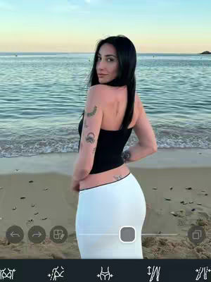 The cover image shows a woman standing on a beach, seen from the waist up, with the ocean and sunset in the background. She is wearing a black top and a white skirt. The sky has a gradient from yellow to blue.  The image has a cool, relaxed tone.
