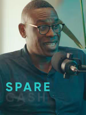 A man in glasses with a microphone in front of him. The word "SPARE CASH" in large, teal letters is overlaid at the bottom.