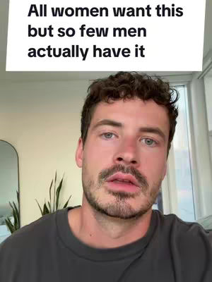 A man with short, dark hair and a short beard is centered in the frame, looking directly at the camera. Above him, a rectangular text overlay reads 'All women want this but so few men actually have it.' The background is blurred, suggesting an indoor setting with neutral tones.