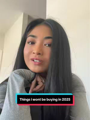 A woman with long dark hair is the central focus of the image. She is wearing a gray sweatshirt and is positioned with a slightly upward angle. A text box that reads "Things i wont be buying in 2025" is overlaid against a black rectangle at the bottom.