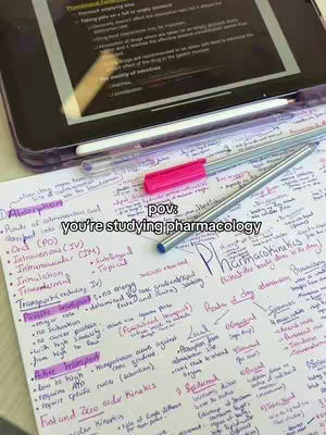 The image shows a close-up of a notebook with detailed pharmacology notes, a tablet displaying additional notes, pens, and a pink highlighter. The notes are handwritten in multiple colors. The layout suggests a study environment. Overlay text reads 'pov: you're studying pharmacology'.