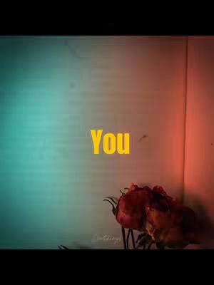 The image features a book with open pages. The left side is lit with a teal-green glow, the right side with a reddish-orange, creating contrasting light. A yellow word "You" is in the center, with roses at the bottom.