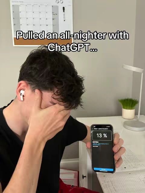 A young man with dark hair is shown in a room, appearing distressed. He is holding his hand over his face, with a phone in his other hand displaying a low battery percentage. The background includes a calendar, a desk, and a lamp.