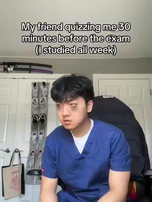 A young man with dark hair and tired eyes is the central figure, wearing a blue scrub top against a cluttered domestic background. Text overlay indicates he may be quizzed by friend before the exam. The background includes a closed door and a decorative item.