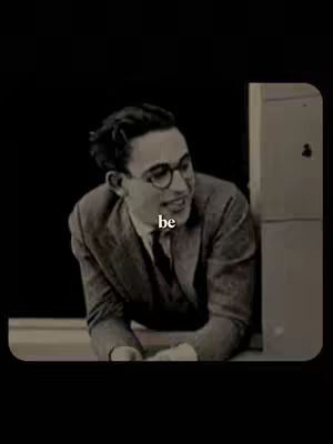 A black and white image features a man in glasses smiling and looking out of a doorway or window. Text 'be' is overlaid.