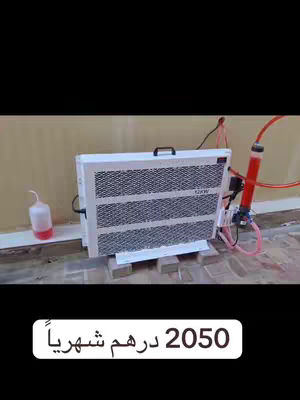 The cover image shows a white rectangular device with visible internal components, likely a cooling system, mounted on a light-colored surface. Attached to it are red and pink tubes and a white, small container with a red liquid. A text overlay shows a text in Arabic. The background consists of an exterior wall and ground.